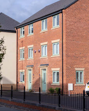 A red brick building with a black fence in front.