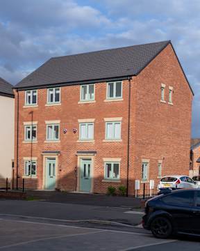 A red brick house with a black car parked in front.