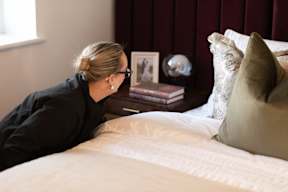 A woman in a black shirt is sitting on a bed.