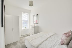 a bedroom with a bed and a dresser and a window