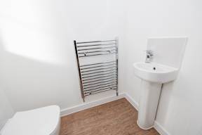 A white toilet sits next to a white sink in a small bathroom.