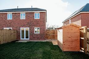 A red brick house with a wooden shed in the backyard.