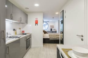 a kitchen with a sink and a stove and a door to a bedroom
