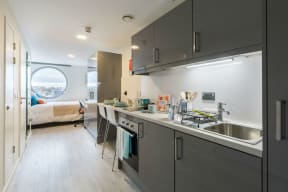 a kitchen with a sink and a bedroom in the background