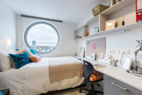 a bedroom with a bed and a desk and a window