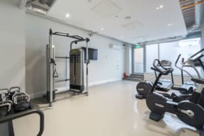 a gym with weights and cardio equipment on the floor and a window