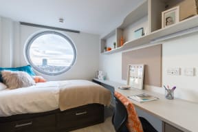 a bedroom with a bed and a desk in a room with a window