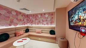 A room with a pink wall and a TV on the wall.