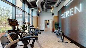 A gym with a row of stationary bikes and a sign that says "SEREN".