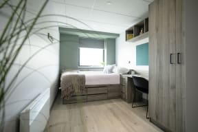 a small bedroom with a bed and a desk and a window