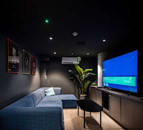 A living room with a blue couch, a black table, and a large screen displaying a blue screen.
