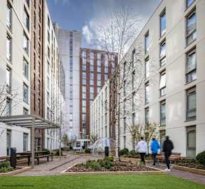 Three people walking in a courtyard between buildings.