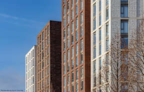 A tall building with a brick facade stands next to a shorter building with a white facade.