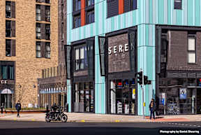 A motorcycle is parked on the side of the street in front of a building with a sign that reads "SERE".
