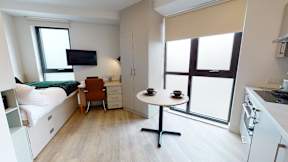 A small room with a bed, a table, and a chair.