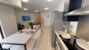 A modern kitchen with a long table and a TV mounted on the wall.