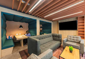 A woman is sitting at a desk in a room with a couch and a chair.