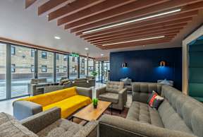 A modern lounge area with wooden slats on the ceiling and grey couches.