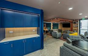 A room with blue cabinets and a grey couch.