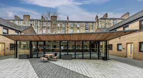 A modern building with a glass entrance and a wooden roof.