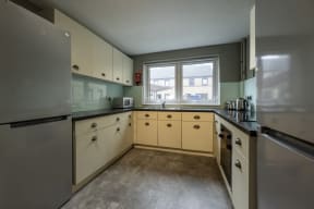 an empty kitchen with white cabinets and a stainless steel refrigerator