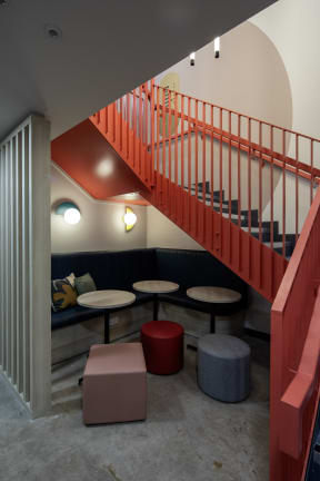 a restaurant with a red staircase and tables and chairs