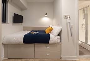 A bedroom with a bed, nightstand, and a television.