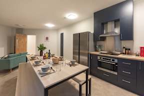 A modern kitchen with a dining table set for two.