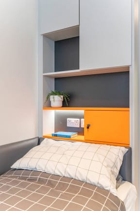 a small bedroom with a bed and a shelf above it