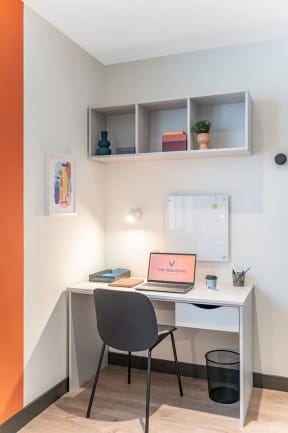 a desk with a laptop and a chair in a room