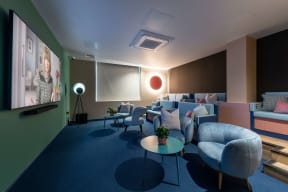 a lounge area with couches and chairs and a projector screen