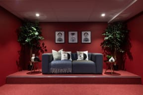 a couch in a room with two plants and a red wall