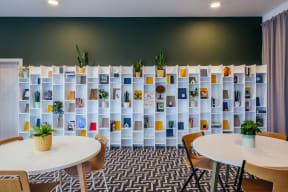 a room with tables and chairs and a wall of plants