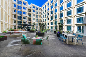 a large patio with tables and chairs in front of an apartment building