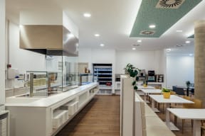 a restaurant with white tables and counters and a kitchen