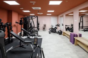 a gym with weights and other exercise equipment in a room with orange walls