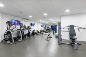 a gym with cardio machines and weights and flat screen televisions