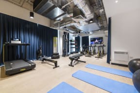 a row of weights and dumbbells in a gym with a wall of black