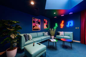 a living room with blue and green furniture and neon lights