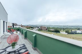 a balcony with a view of a city and a terrace with tables and chairs