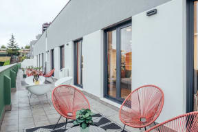 a patio with chairs and tables and a building with windows