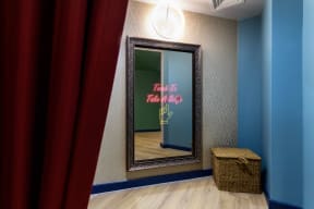 a mirror and a red curtain in a room with a blue wall and a mirror