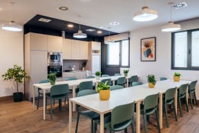 a large meeting room with white tables and chairs and a kitchen