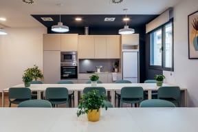 a large white table and chairs in a room with a kitchen