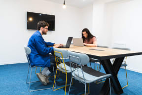 a man and a woman sitting at a table with laptops