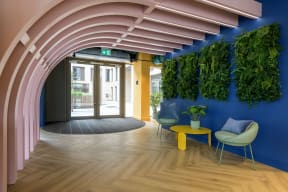 a lobby with blue chairs and a blue wall with greenenery
