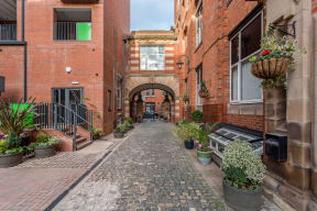 a narrow alley with brick buildings and potted plants