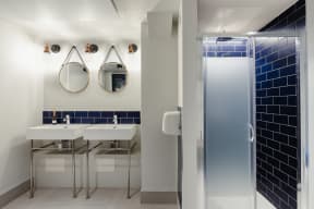 a bathroom with two sinks and a shower and two mirrors