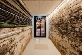 a long hallway with a brick wall and a glass door