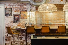 a bar with chairs and a table in front of a brick wall